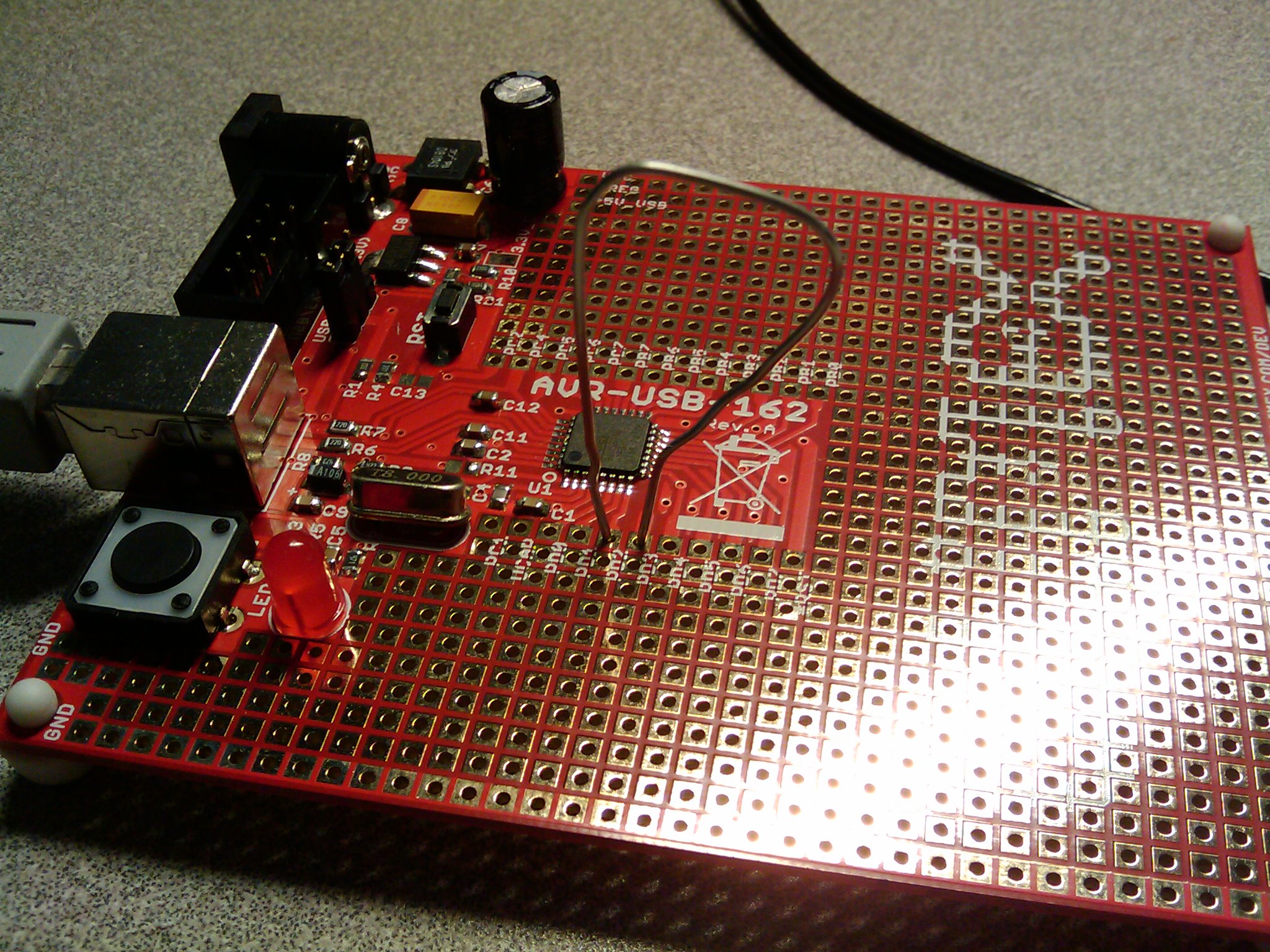 Olimex dev board containing an AT90USB162 microcontroller, with a paperclip functioning as a loopback between TXD1 and RXD1 pins while I played with the sample USB CDC firmware.