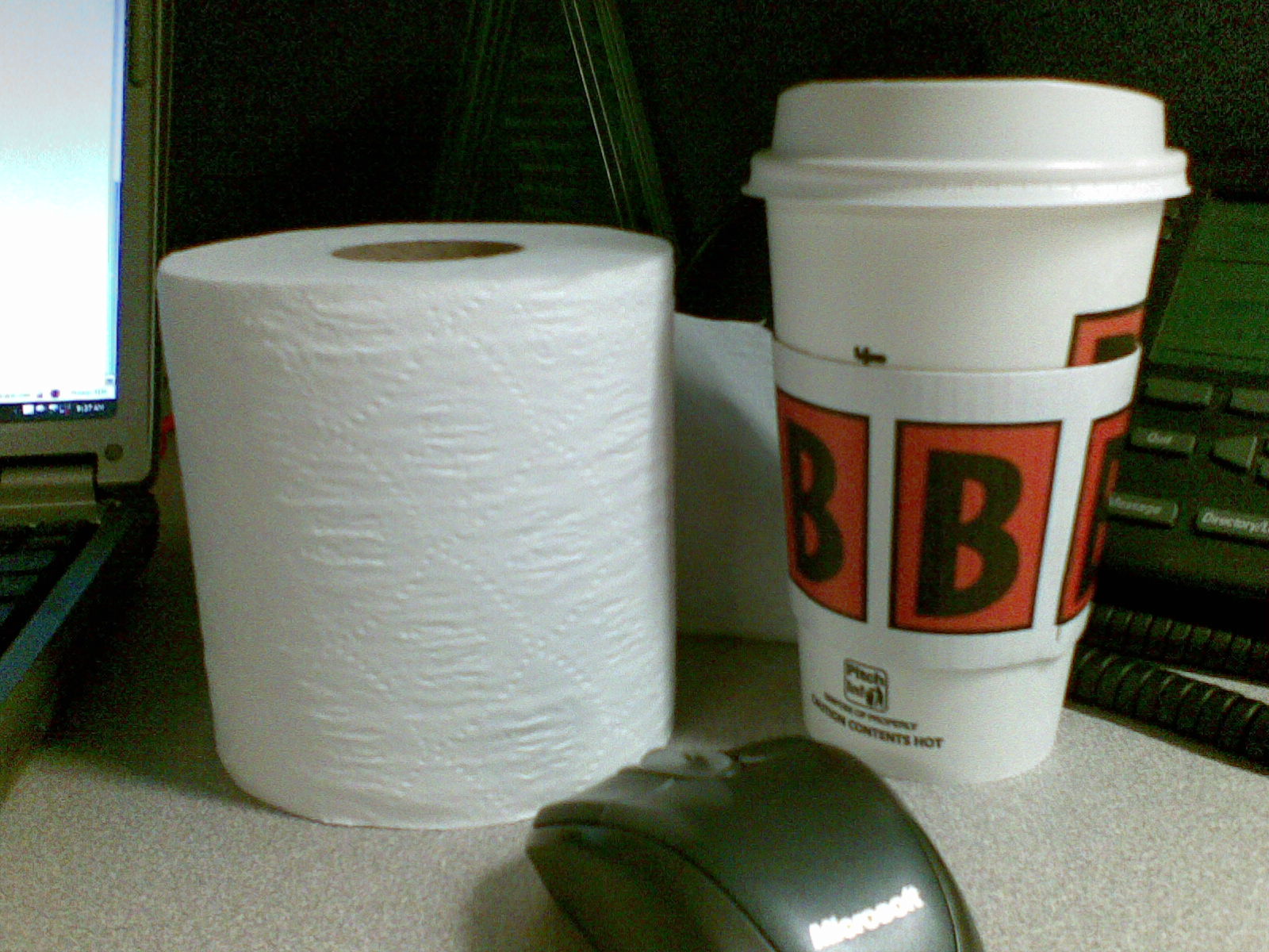 Toilet paper (for my nose) and coffee (for my soul) on a desk at work.