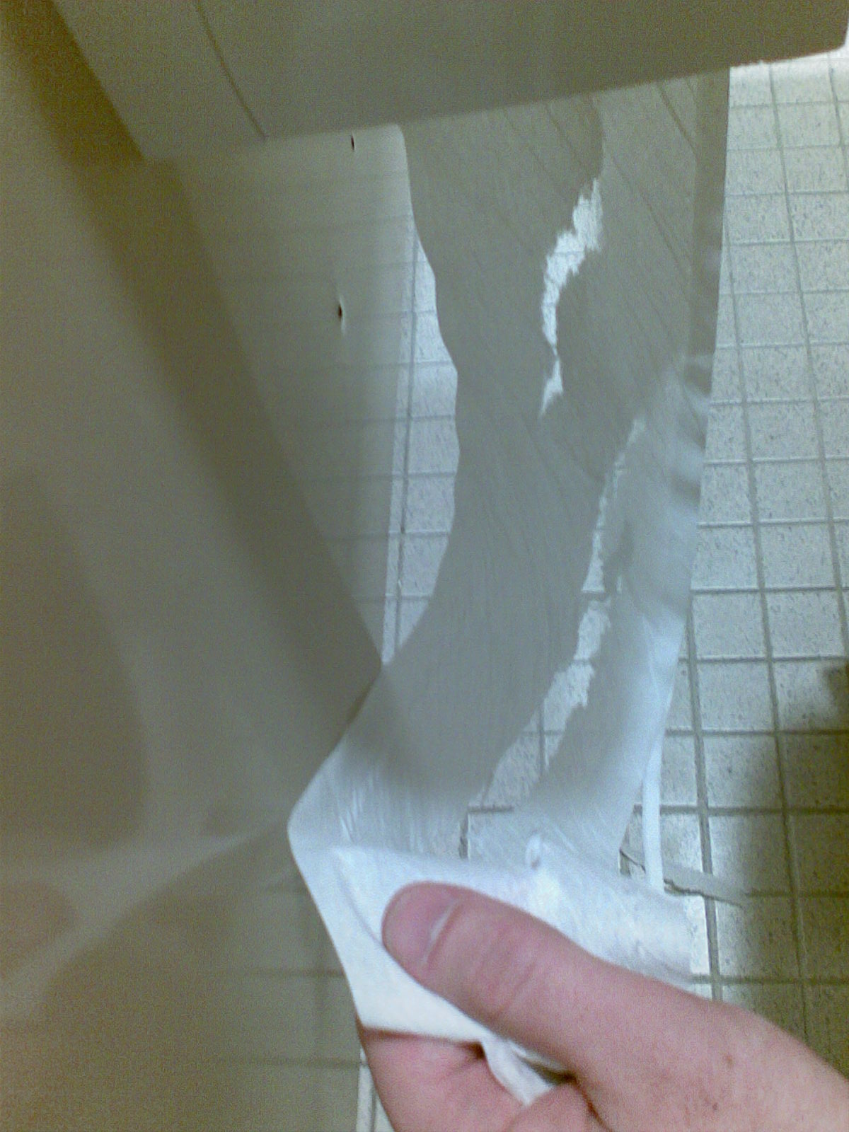 The toilet paper in the middle stall near me is defective, as if someone spilled glue on the roll. It comes out in multiple narrow strips.