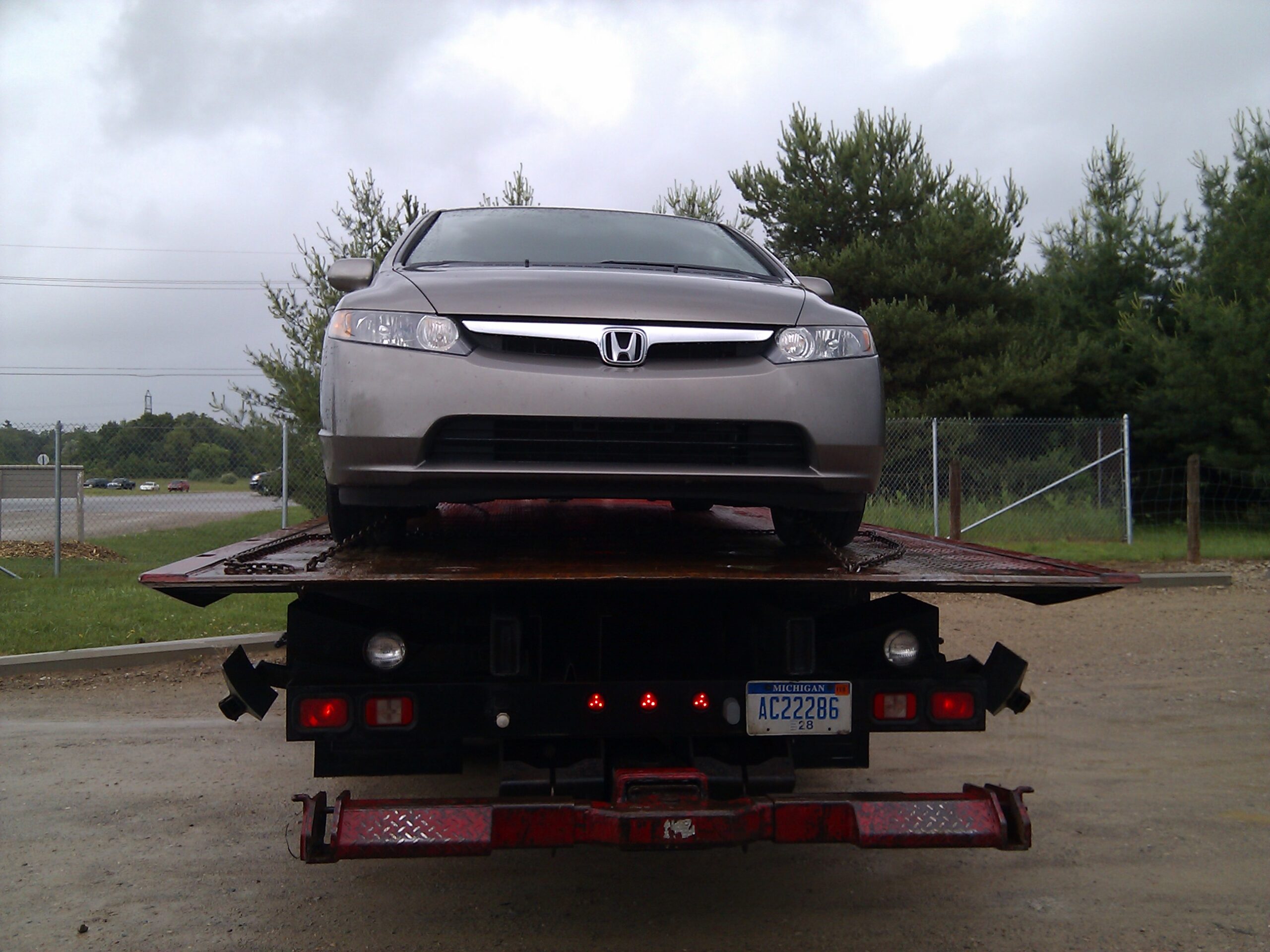 My car sitting on the back of an Adlers Service, Inc. towing company truck (#4) in the Orion Oaks Dog Park lot after something connected to the serpentine belt seized.