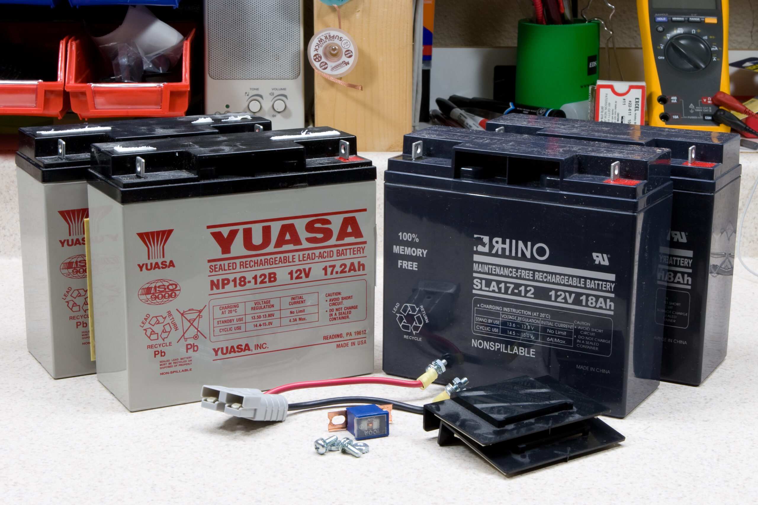 Old Yuasa batteries from my Smart UPS 1400 and the new Rhino version (part SLA-17-12 from Rage Battery) which will replace them. Also shown are the cables, fuse, and fasteners.