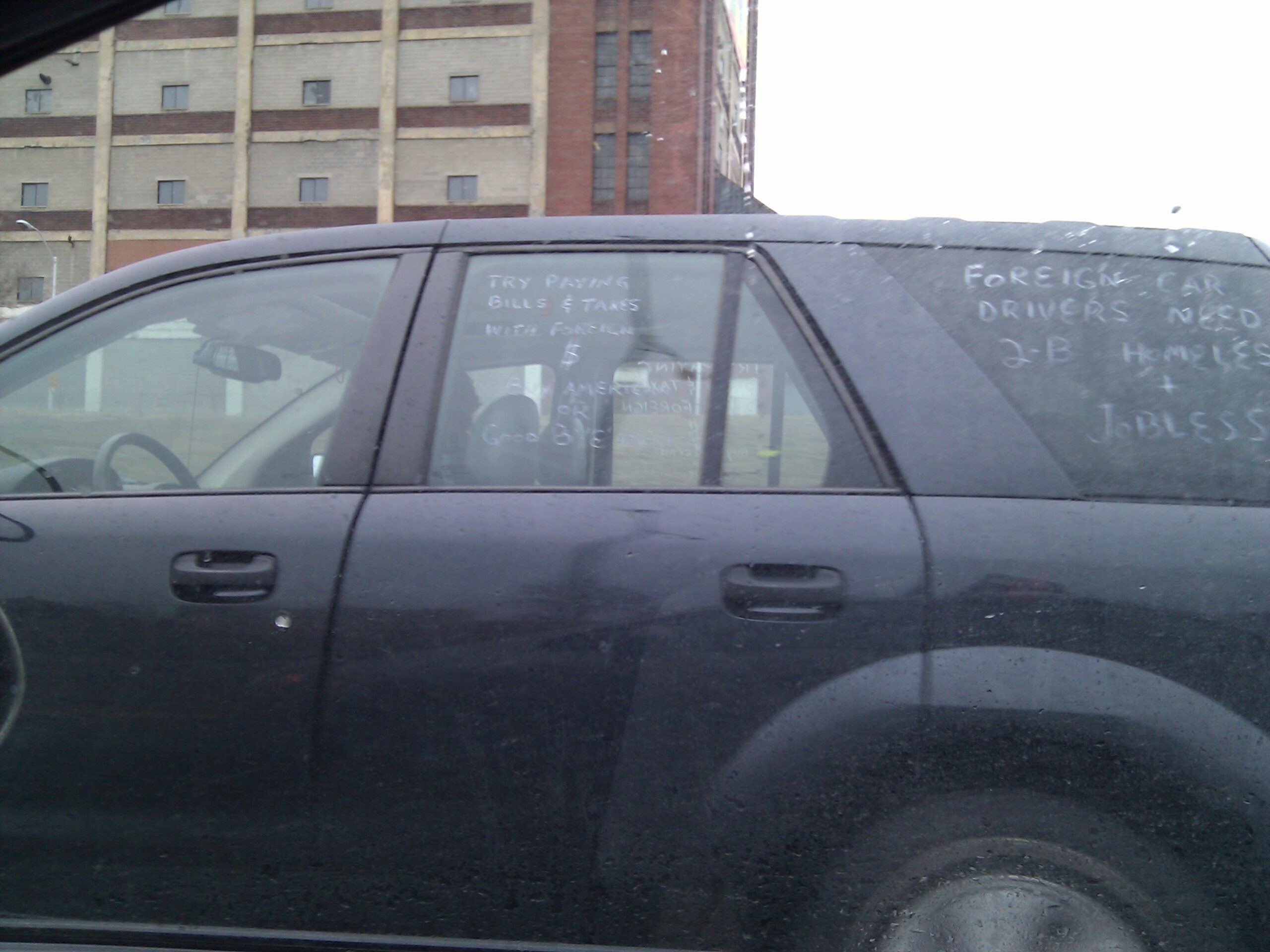 Saturn Vue (Michigan BWB 0564) with hand-written pro-corporate sayings on the windows.