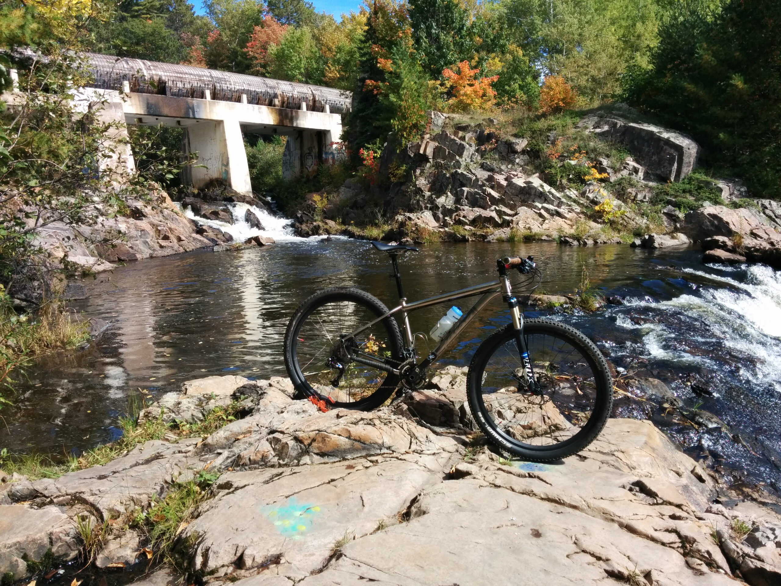 My bike in front of the Dead River and wooden hydroelectric pipe.