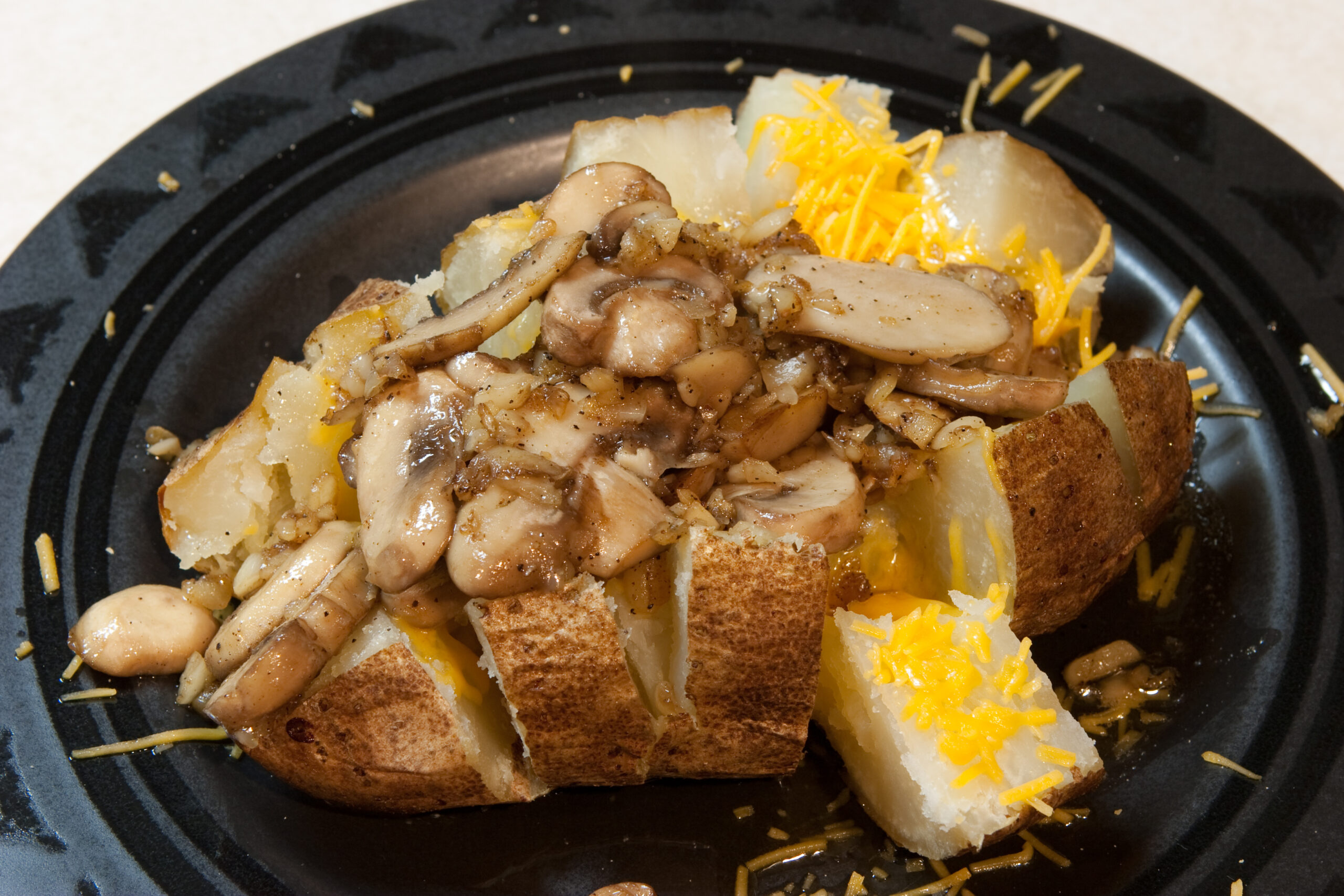 My attempt at a jacket potato. It was baked for 1.5 hours, the topped with shredded cheddar and mushrooms and garlic and black pepper that were fried in butter and olive oil.