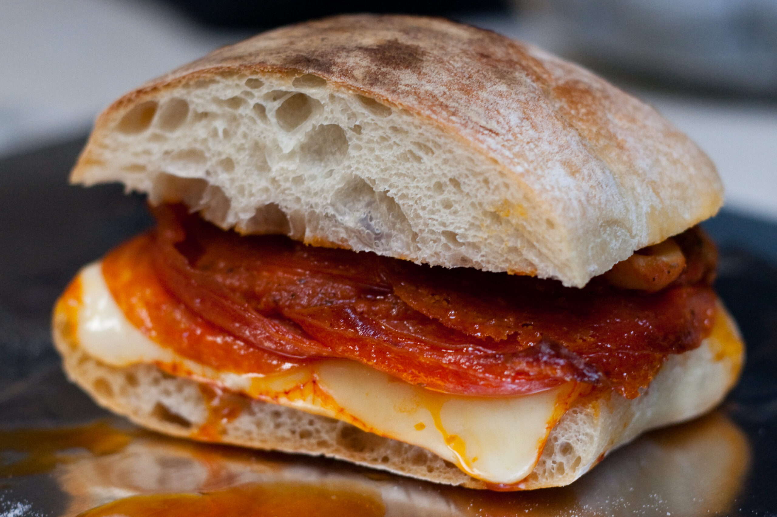 World's greatest pizza sandwich made of cibatta with deli pepperoni, chili tomato mushroom sauce, and muenster, all broiled together.