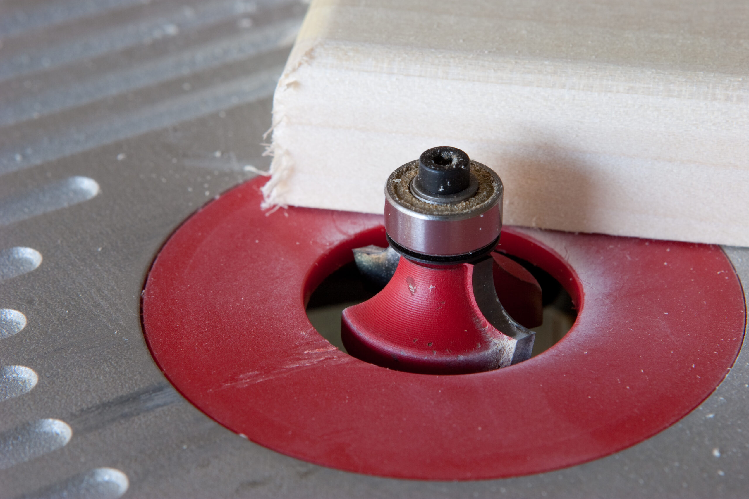 Quarter round bit in a benchtop router, being used to shape some boards to which robe hooks will be attached.