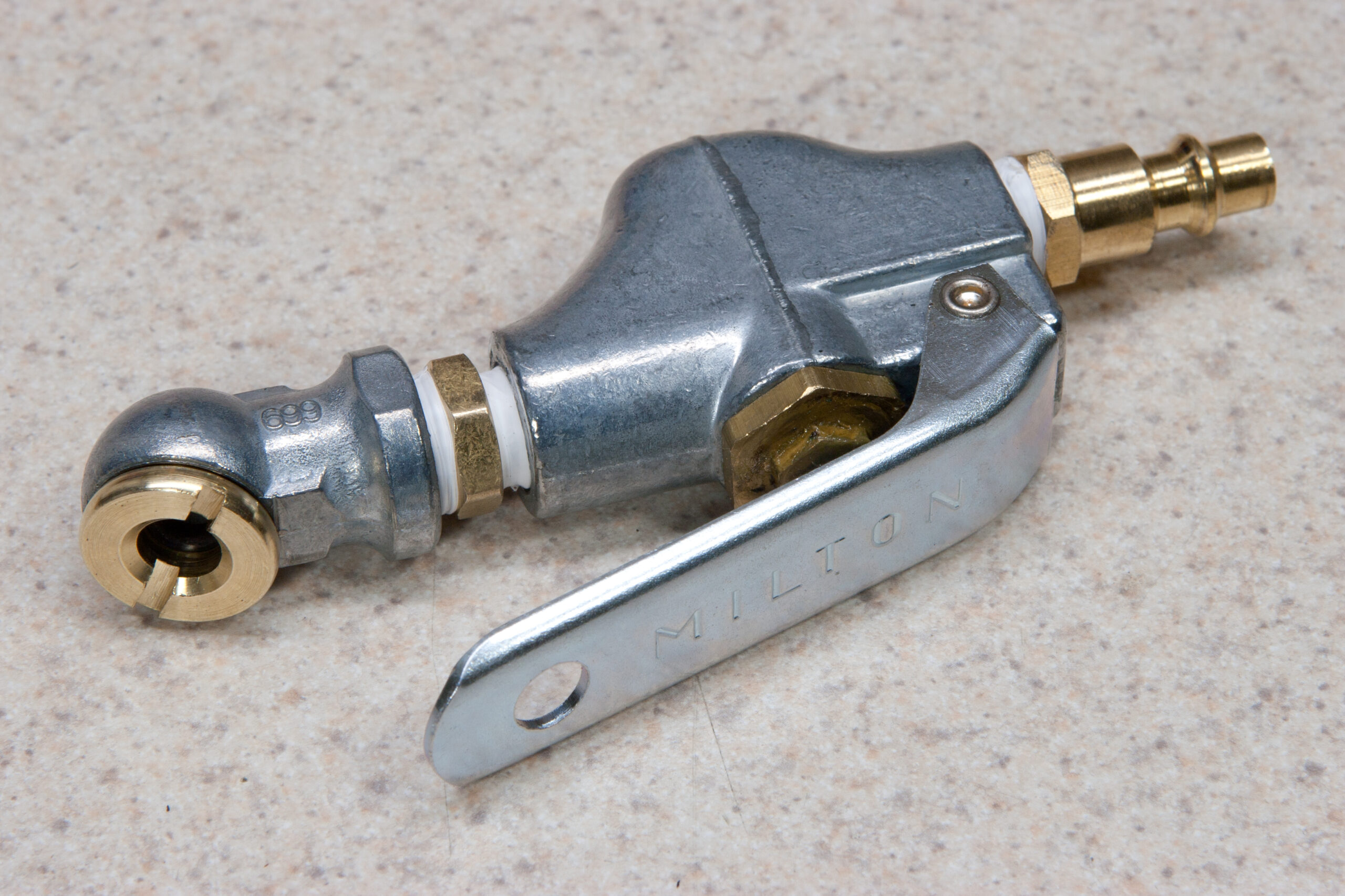 Milton S 153, S 699, 5/16" compression to 1/4" NPT fitting, and 1/4" rubber washer (each modified), and pneumatic quick disconnect to make a high volume inflater for tubeless bicycle tires.