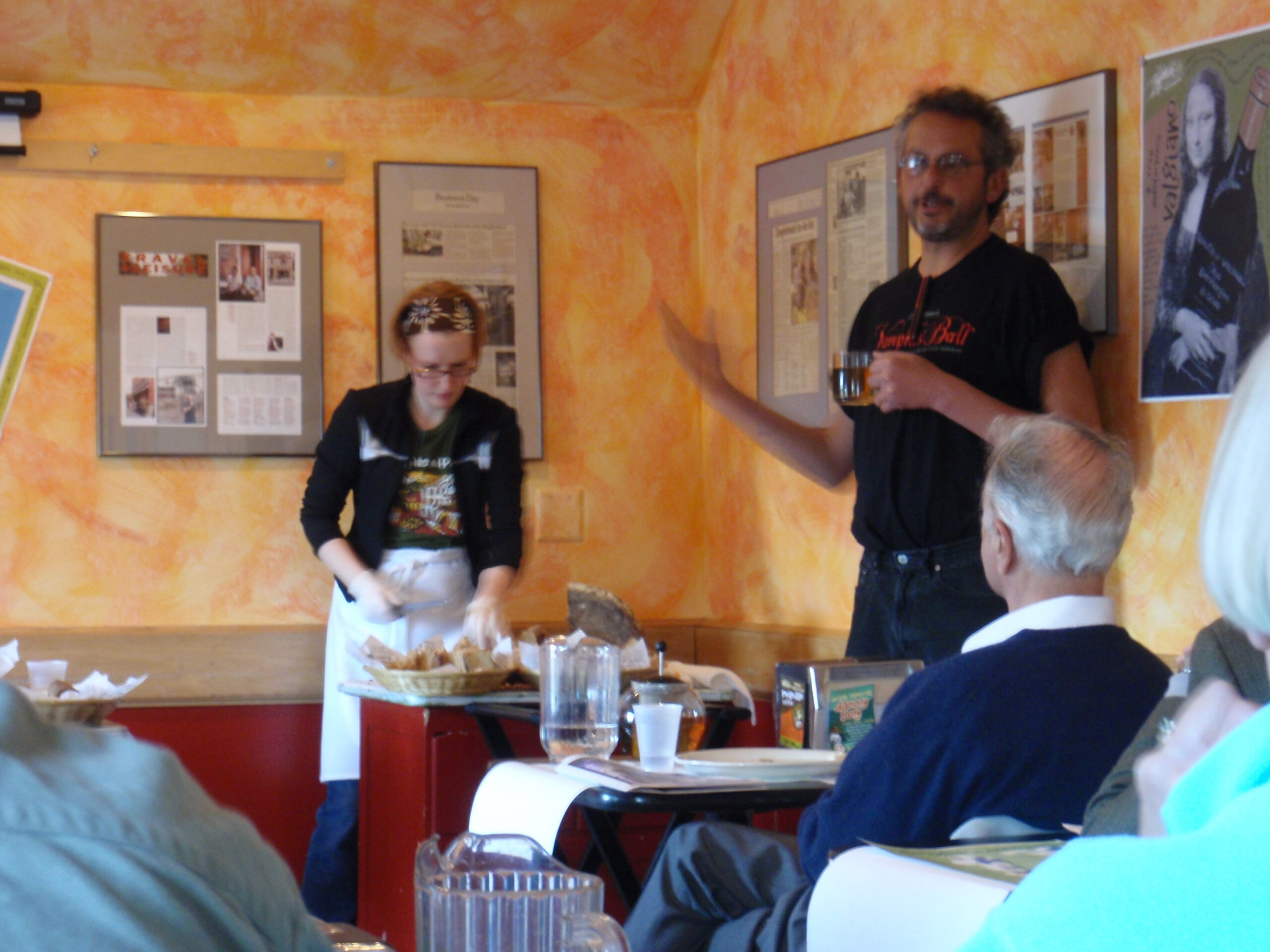 Vanessa cuts bread while Ari Weinzweig gives the introduction at Zingerman's 27th Anniversary Tasting.